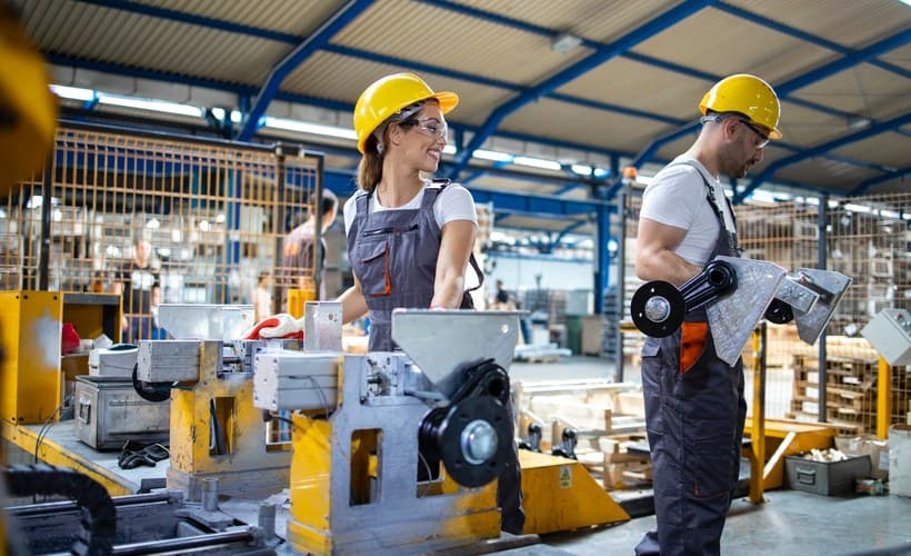 Operators working beside machinery on a factory floor